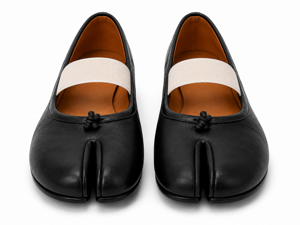A pair of black leather tabi-style flats with a wide off-white fabric band across the top and a small black decorative knot detail on the front, shown against a plain white background.