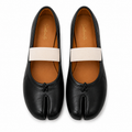 A pair of black leather tabi-style flats with a wide off-white elastic band across the top and a small black tab detail at the toe, shown from a top-down view on a white background.