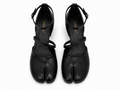 A pair of black leather tabi-style heeled sandals with ankle straps, shown from a top-down view on a white background. The brand name 'Sakura K' is printed in gold on the insole.